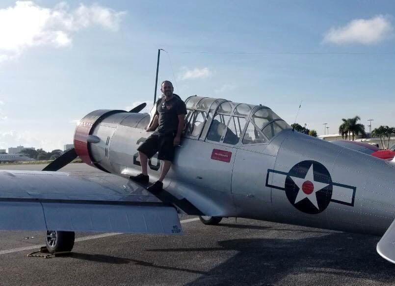 The SEAL Aviation Director of Maintenance posing with a Vultee BT-13 Valiant after assisting repairs
